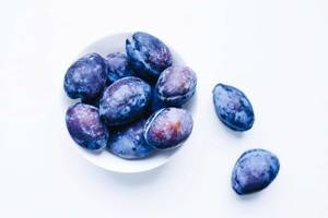 Top view of blue plums in a bowl on white background Top view of blue plums in a bowl on white background