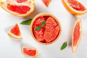 Top view ripe fresh grapefruit slices on white wooden background Top view ripe fresh grapefruit slices on white wooden background