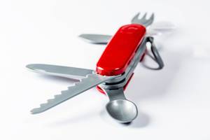 Toy folding knife with fork, spoon, saw and opener on white background Toy folding knife with fork, spoon, saw and opener on white background