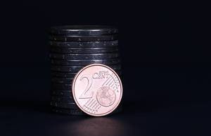 Two Euro cent coin placed in front of piles of coins Two Euro cent coin placed in front of piles of coins
